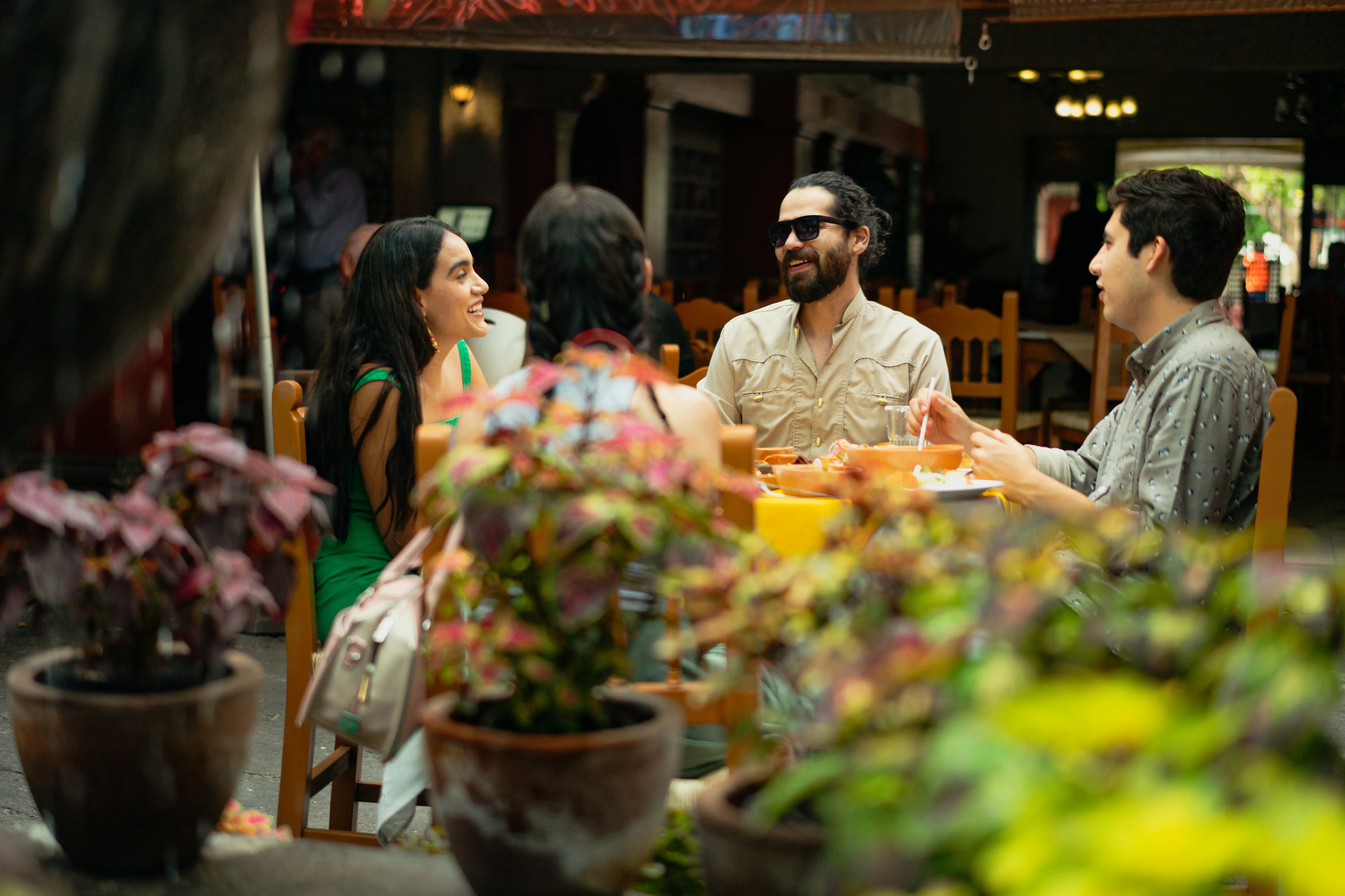 Four people seated at a table outdoors, enjoying a meal and lively conversation.